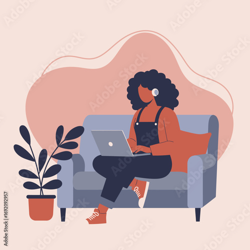 Relaxed woman in headphones working remotely on a laptop from her comfortable home sofa. Ideal for concepts of productivity, online learning, and casual lifestyle.