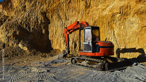 Red bulldozer at quarry site against rugged rock wall. High quality photoRed bulldozer at quarry site against rugged rock wall