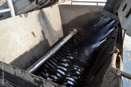 A waste tire crushing machine in operation, with water being sprayed to prevent dust, an industrial process for recycling and environmentally-friendly waste management.