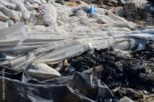 A large pile of oil-soaked absorbents used for an oil spill accident, disposed of on land, illustrating the complex and environmentally challenging process of cleaning up toxic spills.