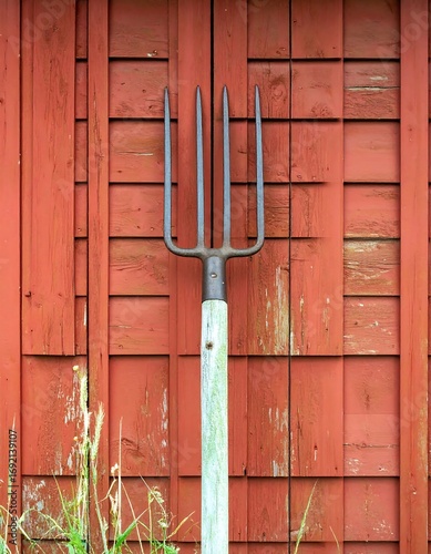 Rustic pitchfork against red shed