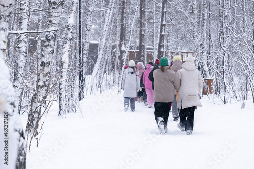 Принти на полотні A group of children and teenagers walking through a winter forest, rear view