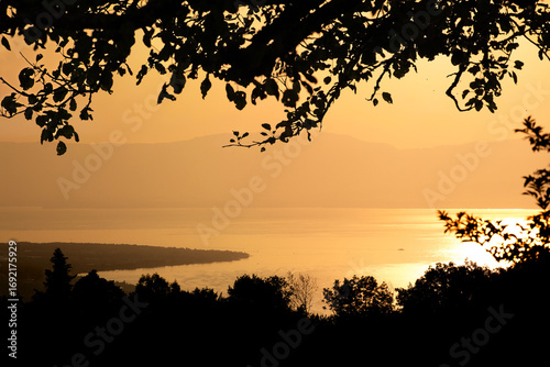 Coucher de soleil sur le lac Léman or brillant depuis les montagnes de la rive française avec vue sur sur la silhouette de la rive suisse. 