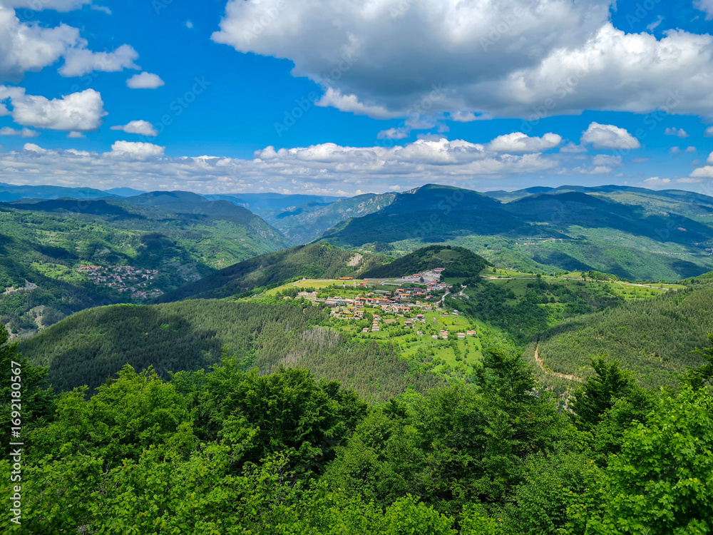 Fototapeta premium Scenic Mountain Landscape with Green Hills, Village and Blue Sky