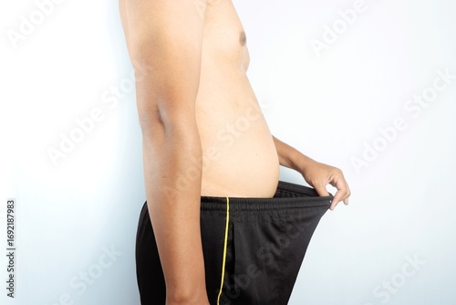 Overweight man holding loose pants