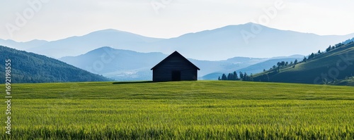 A tranquil landscape featuring a solitary barn amidst rolling hills and vibrant fields.
