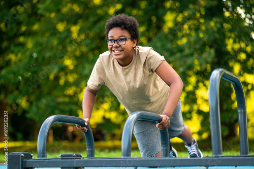 Curly-haired teen exercising at the playground and looking excited