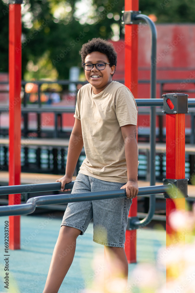 Fototapeta premium Curly-haired boy in eyeglasses spending time at the playground