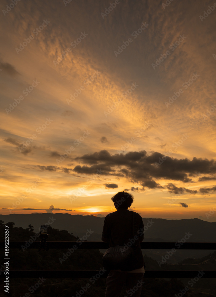 Obraz premium Man enjoying the beautiful sunset over a valley