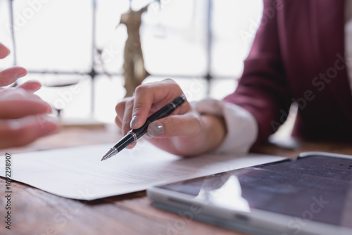 Obraz na plátně Lawyer holding a pen, guiding a client to sign a legal document on a wooden desk