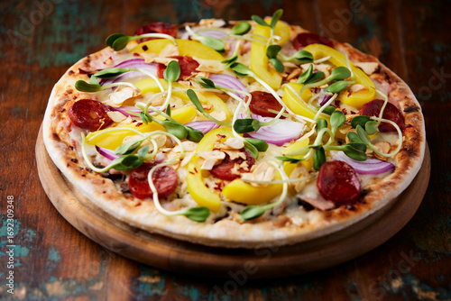 Pizza with chorizo ​​sausage, mozzarella cheese and yellow pepper. Rustic wooden background. Soft focus.