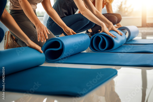 Group of individuals preparing yoga mats in bright studio during morning class session