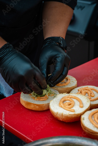 assembling a burger by a chef. bun with sauce and vegetables close-up