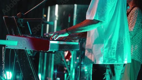 Keyboardist playing piano during worship service, turquoise stage lighting highlighting musical performance with spiritual energy