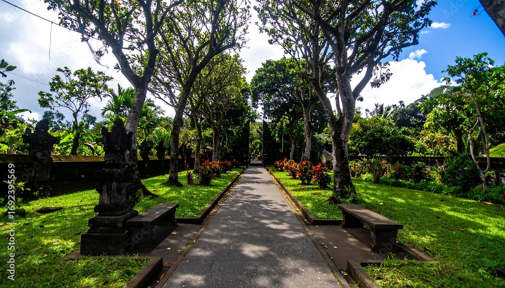 Fototapeta premium Lush tropical garden path lined with ancient statues