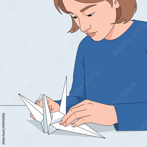 Person folding white paper into a crane on a table.