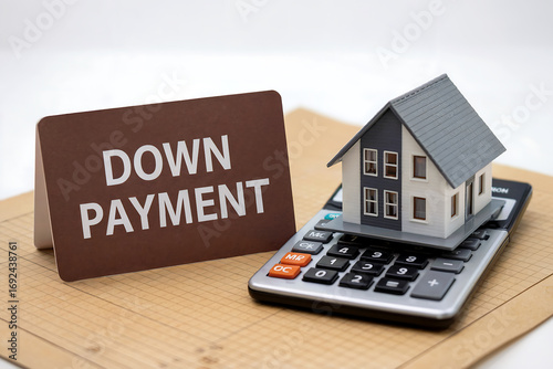 Miniature house on calculator next to down payment sign home real estate