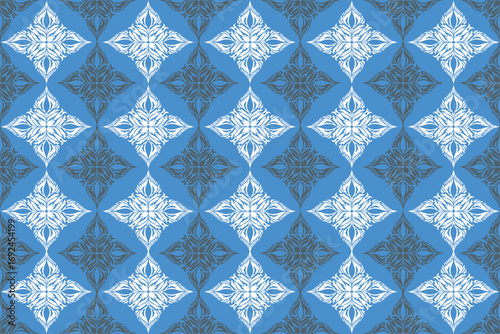 Geometric fabric pattern in blue tones with repeating diamond motifs, featuring white floral shapes alternating with darker intricate designs.