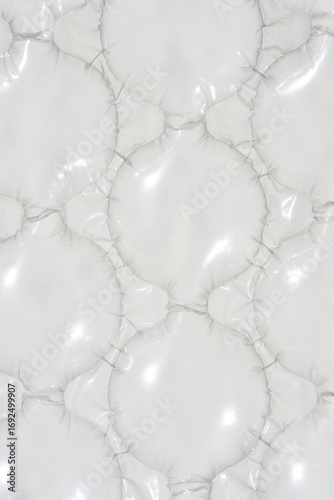 A close-up, abstract shot shows a pattern of connected, light-grey plastic bubbles used for transport, with shiny highlights on their inflated surface