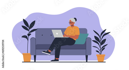 Smiling senior woman actively engaged with her laptop on a cozy sofa at home, showcasing digital literacy and modern lifestyle.