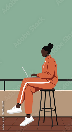 African American woman working remotely on laptop, dressed in a comfortable tracksuit, portraying modern lifestyle, flexibility, and productivity.