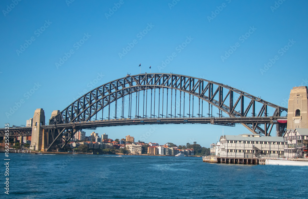 Fototapeta premium Sydney Harbour Bridge with sailing boats and waterfront houses on a sunny day