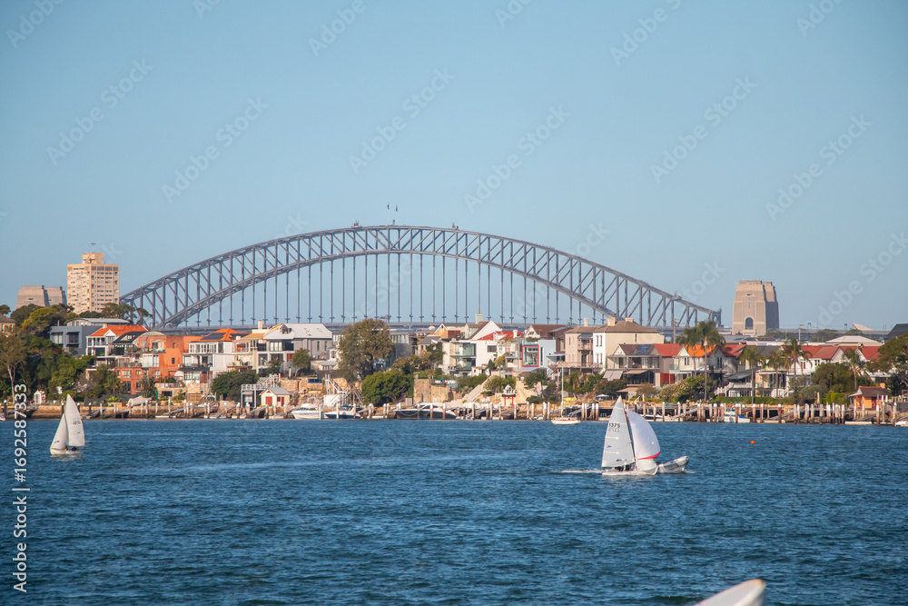 Naklejka premium Sydney Harbour Bridge with sailing boats and waterfront houses on a sunny day