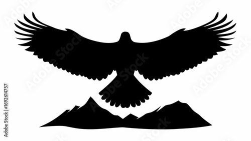 Silhouette of an eagle soaring above a mountain range with outstretched wings in black and white view