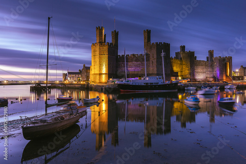 Das Schloss Caernarfon und der Hafen an der Küste von Wales bei Sonnenuntergang