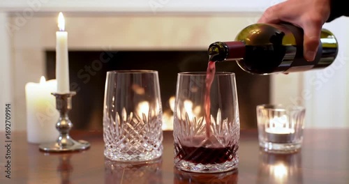 Elegant wine pouring into crystal glasses by candlelight