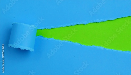 A close-up shot revealing a creative process. Blue paper is torn to expose a vibrant green background. The torn edge adds texture and depth