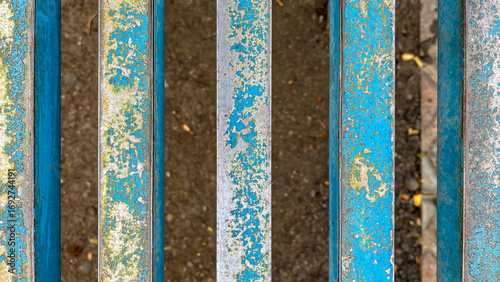 Detailed view of weathered blue metal bars with peeling paint and visible rust, revealing the textured decay over time.