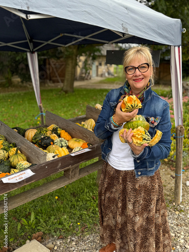 senior woman holding a basket of  pumpkins