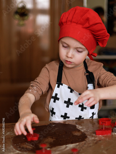 Child cutting Christmas gingerbread cookies with form