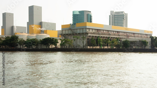 Riverside industry with tall structures and pipelines by the riverside Chao Phraya river in Bangkok Tahiland