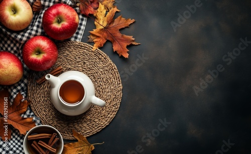 Warm Drink With Cinnamon Surrounded by Apples and Autumn Leaves on a Dark Sur...