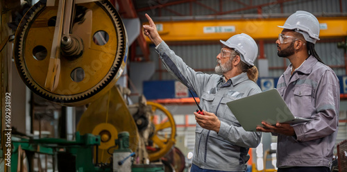 Obraz na plátně Industrial engineers wearing safety gear inspecting heavy machinery in a modern factory