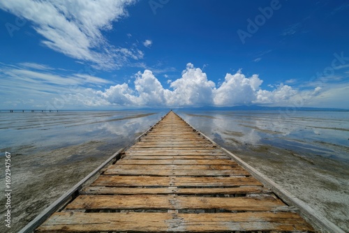 Wooden boardwalk extending into a calm body of water under a vibrant blue sky