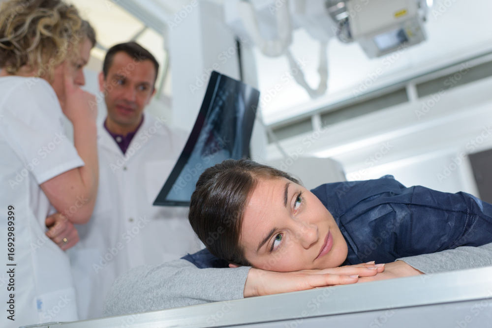 Fototapeta premium patient face-down on stretcher while medics look at xray