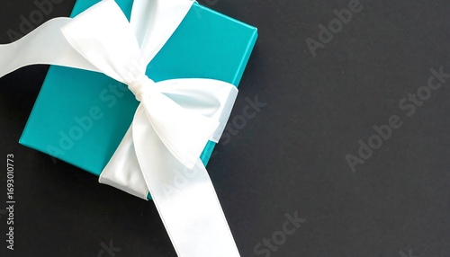 Teal gift box with white ribbon on black background