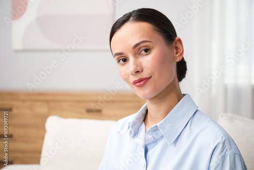 Free Download Elegant woman sitting on sofa at home. Space for text - GFXLoad