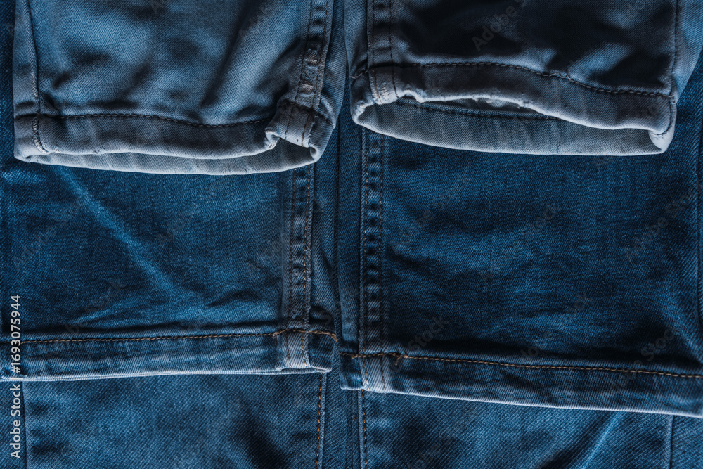 Naklejka premium A close-up stack of blue denim jeans with visible pocket textures and seam details.