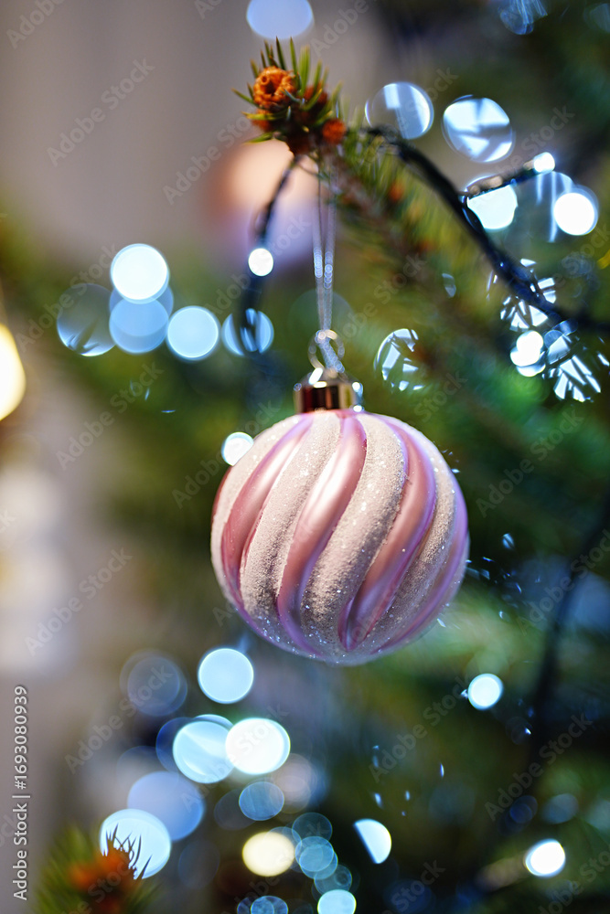 Obraz premium A Christmas decoration in the shape of a ball hanging on a branch of a Christmas tree