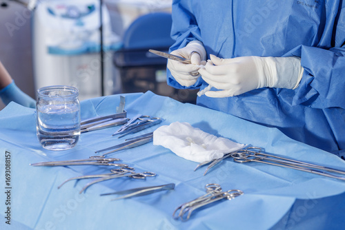 Gloved hands arranging surgical instruments on sterile field in the operating room
