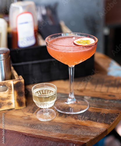 Fotografia Pornstar Martini cocktail on a bar counter with beautiful bokeh in the backgroun