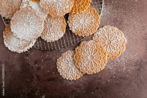 Top View of Pizzelles on a Wire Cooling Rack on a Cookie Sheet Sprinkled with Powdered Sugar