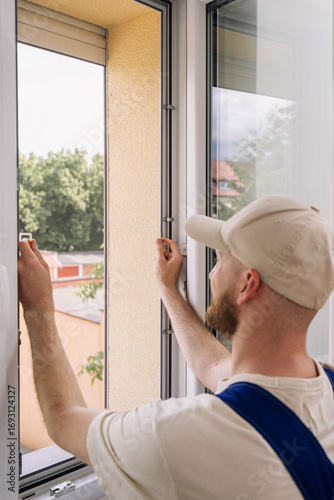 Repairman installs energy-efficient PVC window frame in residential apartment
