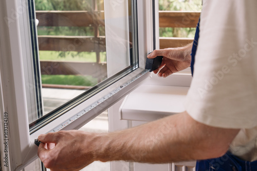 Repairman measures PVC window frame for home installation