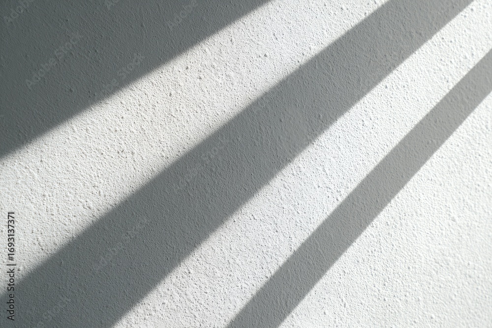 Fototapeta premium Sunlight casts parallel shadows on textured wall