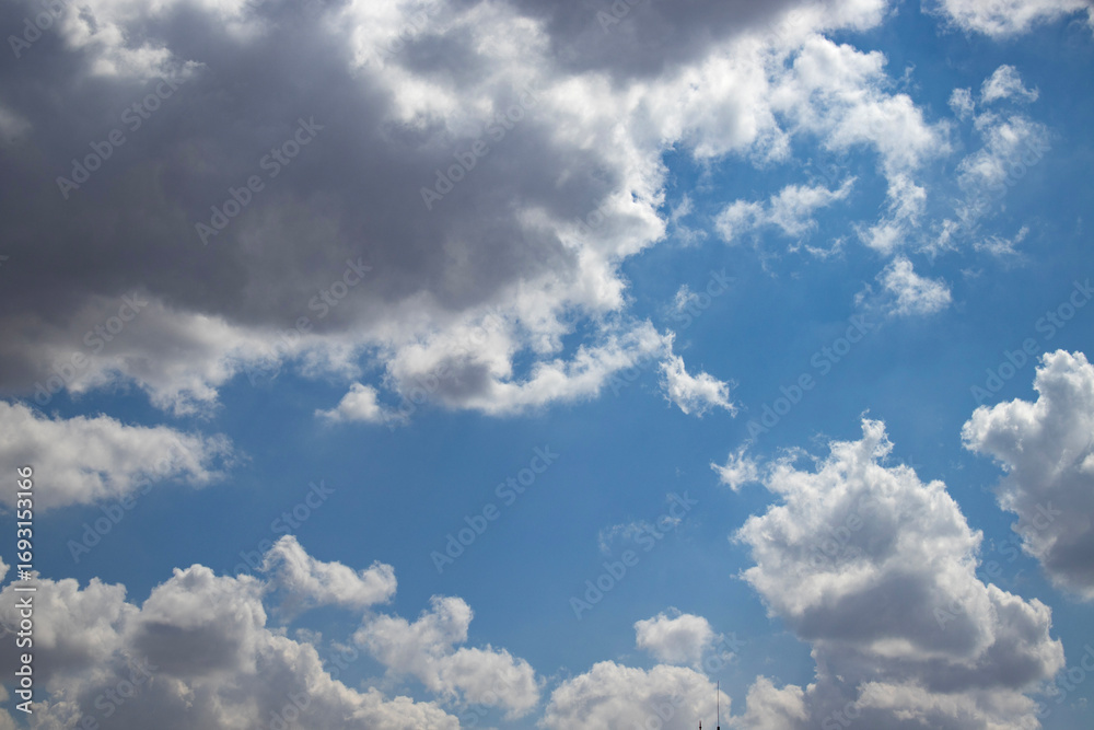 Obraz premium Wide view of blue sky with bright cumulus and dark storm cloud. Natural weather background for banner, poster, wallpaper, climate concept, meteorology theme, travel mood, copy space, web and print.